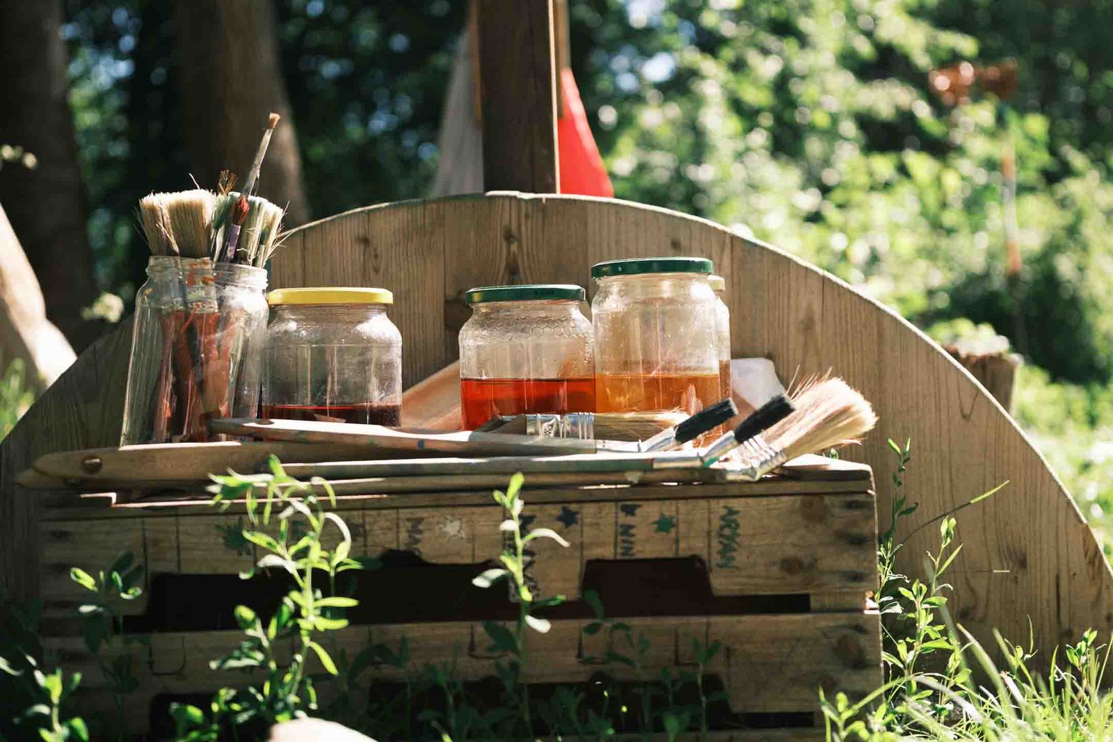 Maltisch im Wald mit Pinseln und Farbgläsern